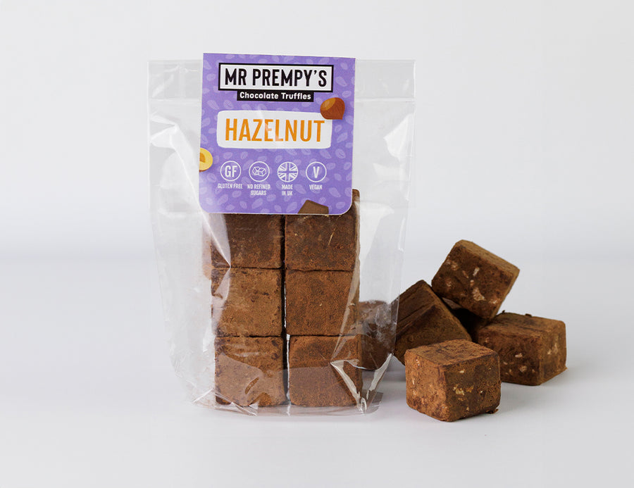 Pack of Mr Prempy's vegan hazelnut chocolate truffles with loose truffles beside it